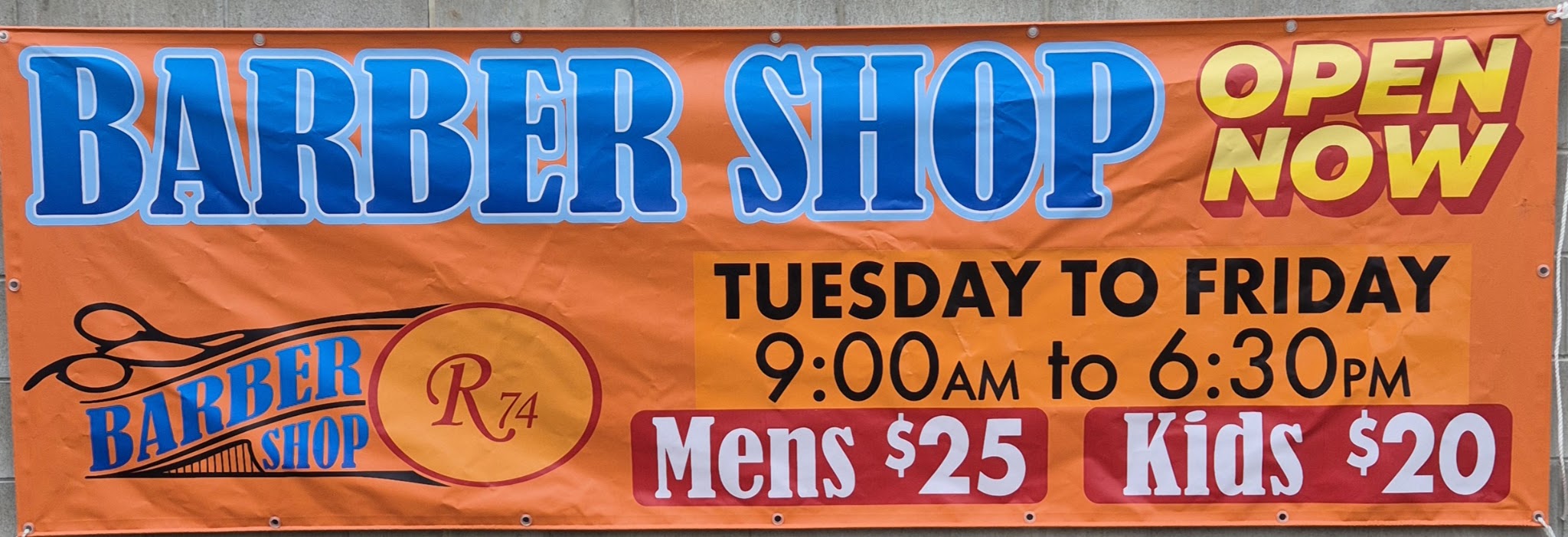 R74 Barber Shop's orange banner sign: Barber Shop, open now, Tuesday to Friday, Mens $25, Kids $20